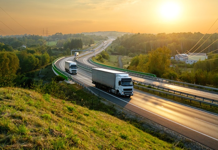 White,Trucks,Driving,On,The,Highway,Winding,Through,Forested,Landscape
